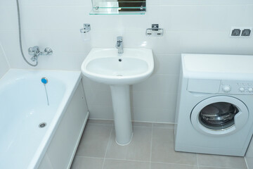 Bathroom with washing machine. Small bathroom. Bathroom interior in light colors. Walls are covered with light-colored tiles. Sink and and fragment bath. Concept - sale of sanitary ware.