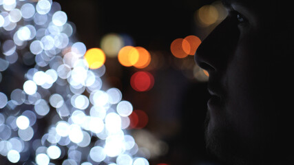 Fototapeta premium Bokeh view of a stylish young handsome man smoking electronic cigarette and breathing out smoke thru nose in city at night in summer