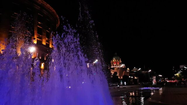 Illuminated Fountain in Downtown Belgrade, Serbia at Night. National Assembly in Background