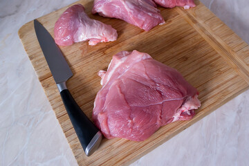 On the cutting board is a knife and pieces of sliced pork for cooking