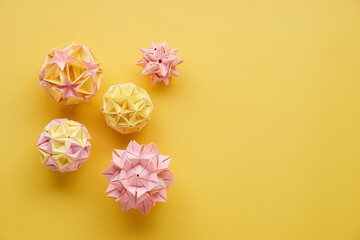 Set of multicolor handmade modular origami balls or Kusudama Isolated on yellow background. Visual...