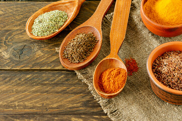 Powder spices on spoons on wooden background