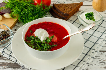 Traditional Ukrainian Russian borscht with garlic and bread. A bowl of red beetroot borscht on a white wooden table. Beetroot soup. traditional slavic cuisine.
