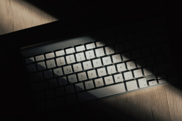 Close-up of a  keyboard in the morning sun with dark shadow. Hard shadows, light.