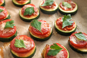 Oven baked zucchini snack with tomato, cheese and parsley garnish, vegetarian mini pizza for a healthy low carb diet, close up shot