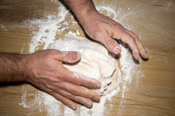 hands kneading dough on table