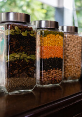 Potrait shot of jars fill up with ingredients kept near window and blurred in the background.