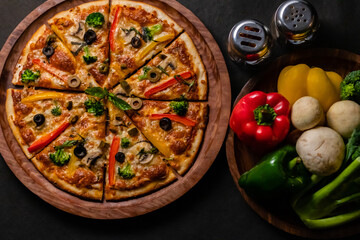 Top view of Picante pizza with vegetables kept on right side on black surface.