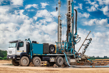 Work of a drilling rig at a construction site against a background of blue sky. Exploration of...