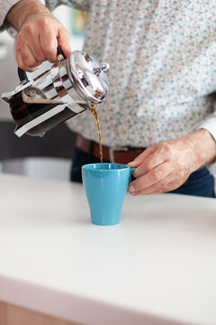 Close Up Of Senior Man Spilling Hot Drink After Preparing Coffee Using French Press In Kitchen For Breakfast. Elderly Person In The Morning Enjoying Fresh Brown Cafe Espresso Cup Caffeine From Mug