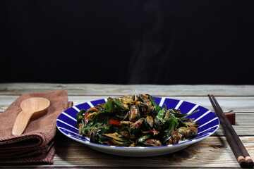 Fried spicy mussel meat with chilly and basil serving on the plate. Famous traditional seafood menu in Asia restaurant. 