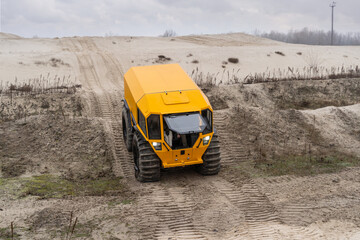 Fototapeta na wymiar Yellow all-terrain vehicle driving in a hilly sandy landscape