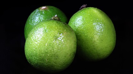 three green limes with drops on turntale with black background