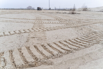 Big tire marks in the sand and an off-roader in the distance