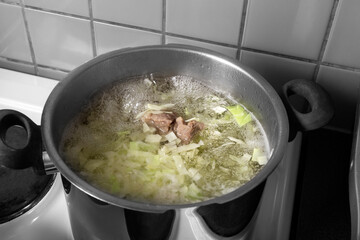 The souA casserole of soup is on the stove in the home kitchen. Meat in a saucepan.p is cooked in a saucepan. High quality photo