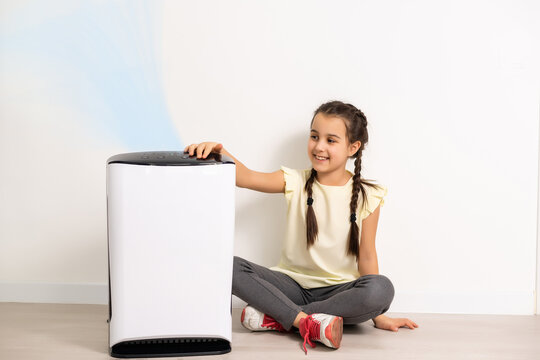 Cute Little Girl Standing Breathing At Air Purifier. Clean Air Concept