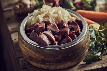 Bowl with fresh liver placed on table near various veggies