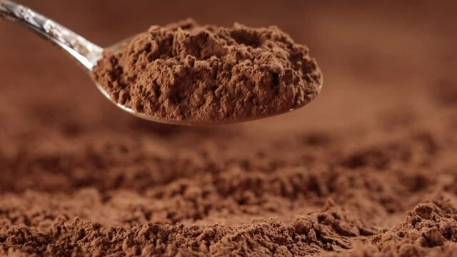 cocoa powder is poured from a spoon close up slow motion