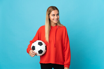 Young football player woman isolated on blue background looking side