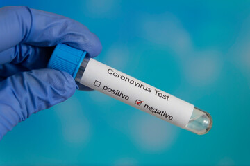 Obraz premium Coronavirus vaccine test negative positive in glass test tube covid on blue blue background children's hand