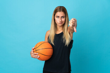 Young woman playing basketball  isolated on white background showing thumb down with negative expression