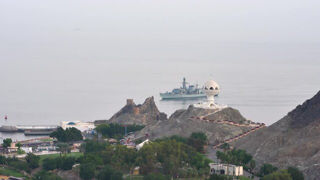Giant Incense burner in Al Riyam Park with boats and ships moving in fast motion (timelapse) in Mutrah. Muscat, Oman
