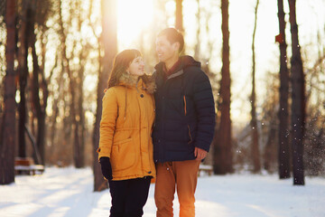 Warm winter portrait of young interracial smiling couple on a walk in the forest
