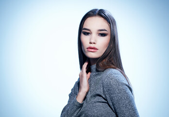 Beautiful woman model in a gray sweater with dark hair Makeup on the face