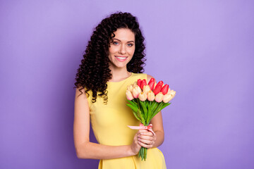 Portrait of attractive satisfied lady arms hold flowers beaming smile look camera isolated on purple color background