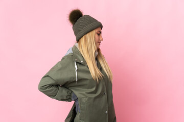 Young woman with winter hat isolated on pink background suffering from backache for having made an effort