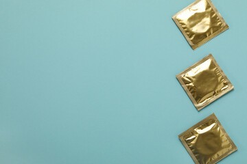 Blank condoms on light blue background, space for text