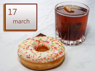 March 17 ,17th day of the month. Calendar with date and a cupcake with glass of tea on table at home.. Spring month. Day of the year concept.