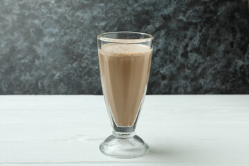Glass of chocolate milkshake on white wooden table