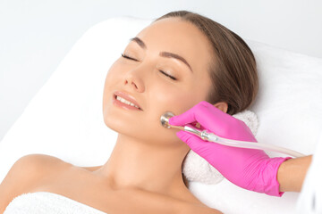Cosmetologist makes  procedure microdermabrasion on the face against acne and blackheads. Women's cosmetology in the beauty salon.