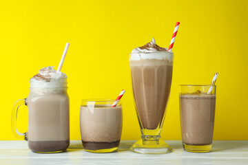 Glasses of chocolate milkshake against yellow background