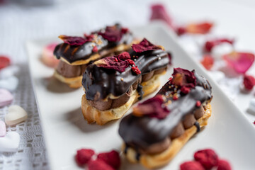 creamy chocolate eclair with edible flowers, rose petals and freeze dried raspberries  - 415993027