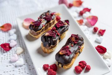 creamy chocolate eclair with edible flowers, rose petals and freeze dried raspberries 