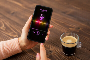 Woman having coffee and listening to podcast on her phone while