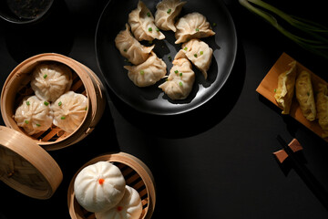 Dimsum on plate and bamboo steamer with dumplings and pork buns