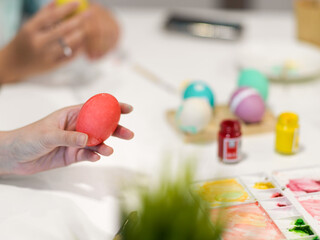 Female hold holding pink egg while painting Easter egg for Easter festival