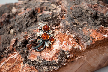 Decoration of amber and bronze in the form of a flower on a wooden background