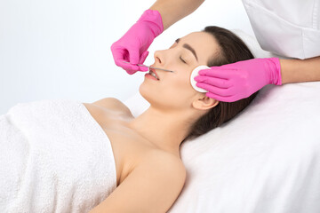 A procedure for cleansing the skin of the face from blackheads and acne. Cosmetologist treats problematic skin of a young woman's face in a beauty salon. Aesthetic cosmetology and makeup concept.