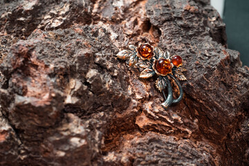 Decoration of amber and bronze in the form of a flower on a wooden background