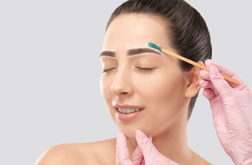 Makeup artist does facial hair removal procedure. Beautiful girl with blue eyes having Permanent...