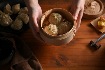 Female hands holding a bamboo steamer of Dimsum dumplings to serve in restaurant