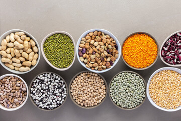 Different types of legumes in bowls, green and yellow peas, chickpeas and peanuts, colored beans and lentils, mung beans and beans, top view