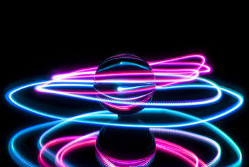 Circular light painting around a glass ball on a black backgtound with reflection.