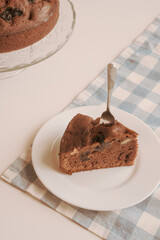 Chocolate pie on a white plate with a spoon on the blue checkered tablecloth. Vintage style. Selective focus