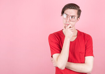 young man with glasses and red t-shirt thinks about things