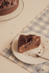 Chocolate pie on a white plate with a spoon on the blue checkered tablecloth. Vintage style. Selective focus